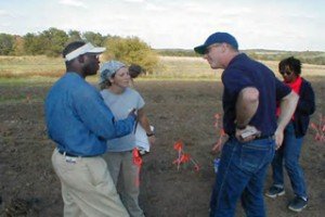 Survey Members Discussing the Next Step The Eyes Have It Student volunteers walk plowed area on New Philadelphia town site, marking artificants they discover with colored flags. Supervisors and other volunteers follow behind them, bagging and cataloguing the artifacts. The completed report from this survey can be seen at New Philadelphia Project Field Walkover Survey .